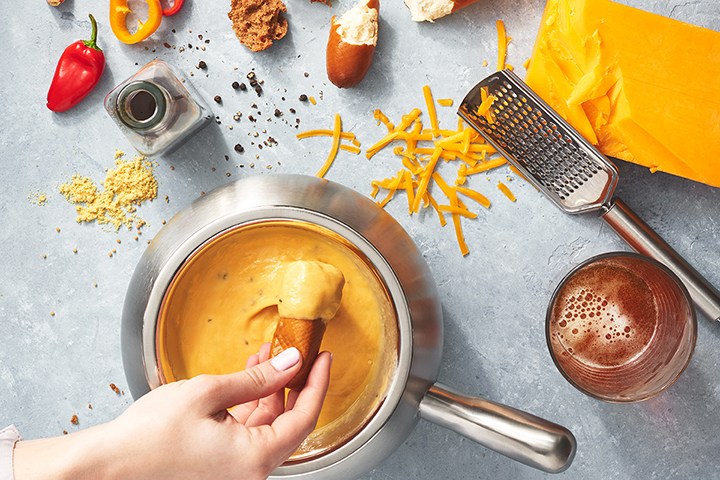 a person holding a waffle cone over a pot of cheese fondue